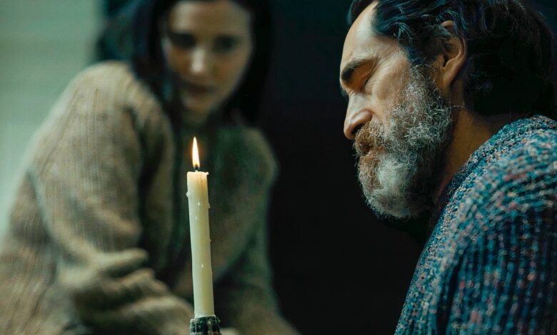 demian bichir stares at a candle while julia goldani telles stares in the background in beacon