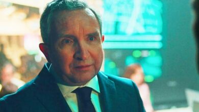 eddie marsan in supacell wearing a suit with a bustling headquarters behind him